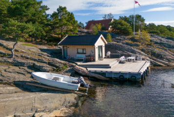 Liten båtbod eller naust ved sjøen, med brygge og båt, omgitt av natur og klipper. Perfekt for båtliv og avslapning i skjærgården.